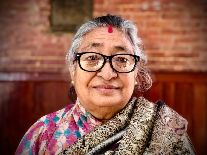 An Elderly Woman Wearing Black Framed Eyeglasses with Tika on Forehead